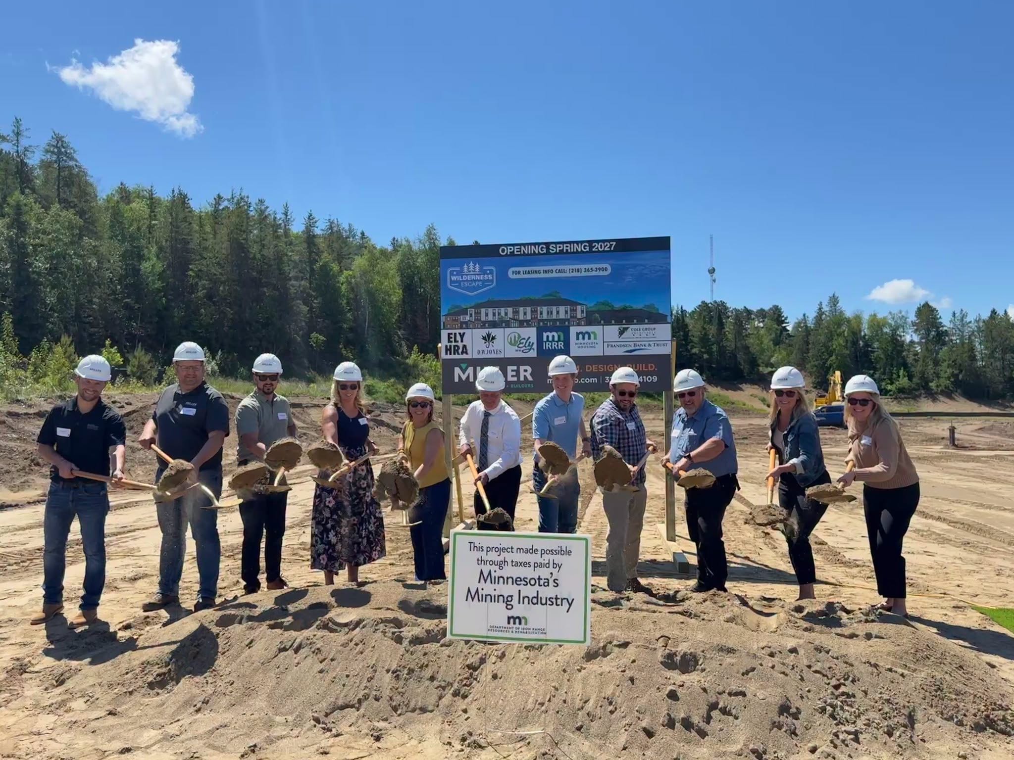 Wilderness Escape groundbreaking Community leaders in hard hats break ground at the Wilderness Escape workforce housing site in front of the project sign